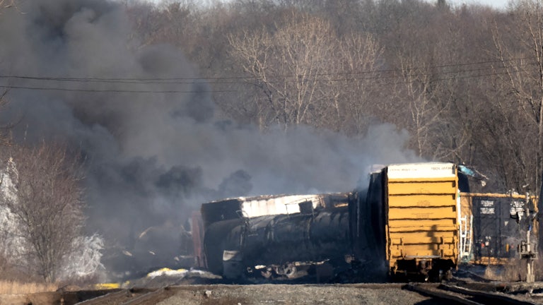 Cargo train lays off the tracks, as smoke rises