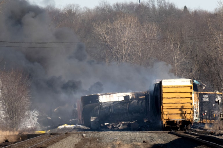 Cargo train lays off the tracks, as smoke rises