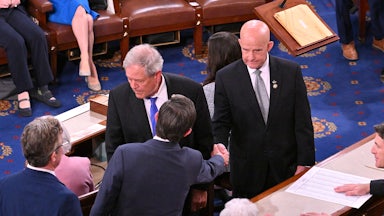 Keith Self and Mike Johnson shake hands surrounded by colleagues.