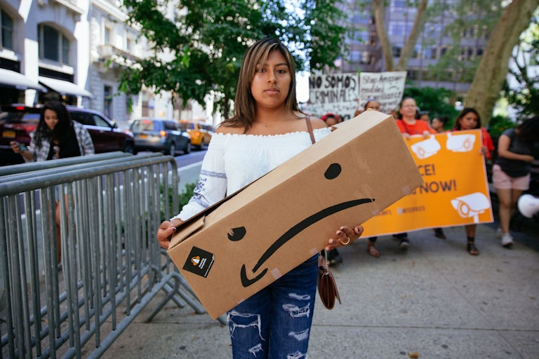 A protester holds an Amazon box while demonstrating against Jeff Bezos.