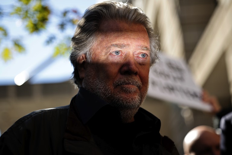 Steve Bannon stands in a ray of light amidst shadows