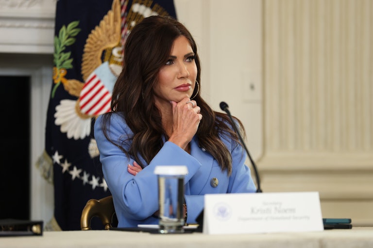 Homeland Security Secretary Kristi Noem sits at a table with her hand on her chin