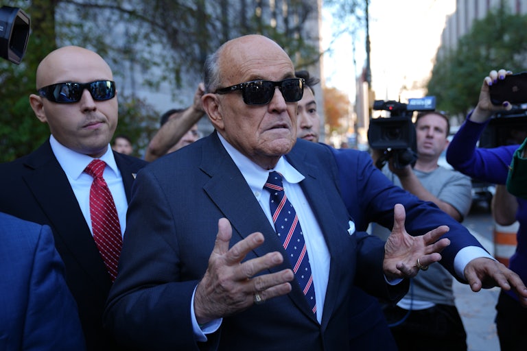 Rudy Giuliani holds up his hands while speaking to reporters