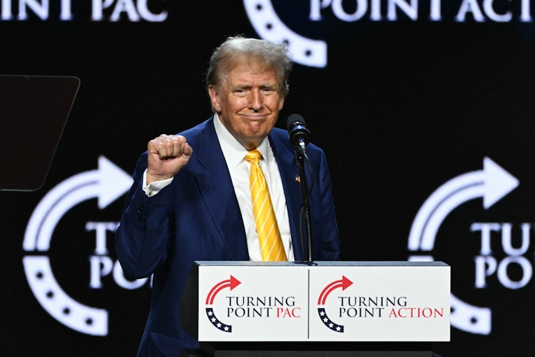 Donald Trump holds up his fist as he stands at a podium