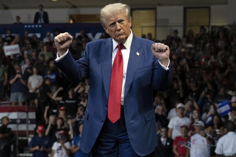 Donald Trump holds up his fists while on stage at a campaign event