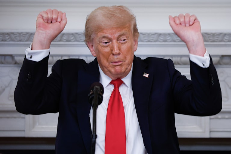 Donald Trump raises his fists above his head while standing at a podium
