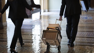 Documents including the text of the bipartisan infrastructure legislation are wheeled toward the office of Senate Majority Leader Chuck Schumer