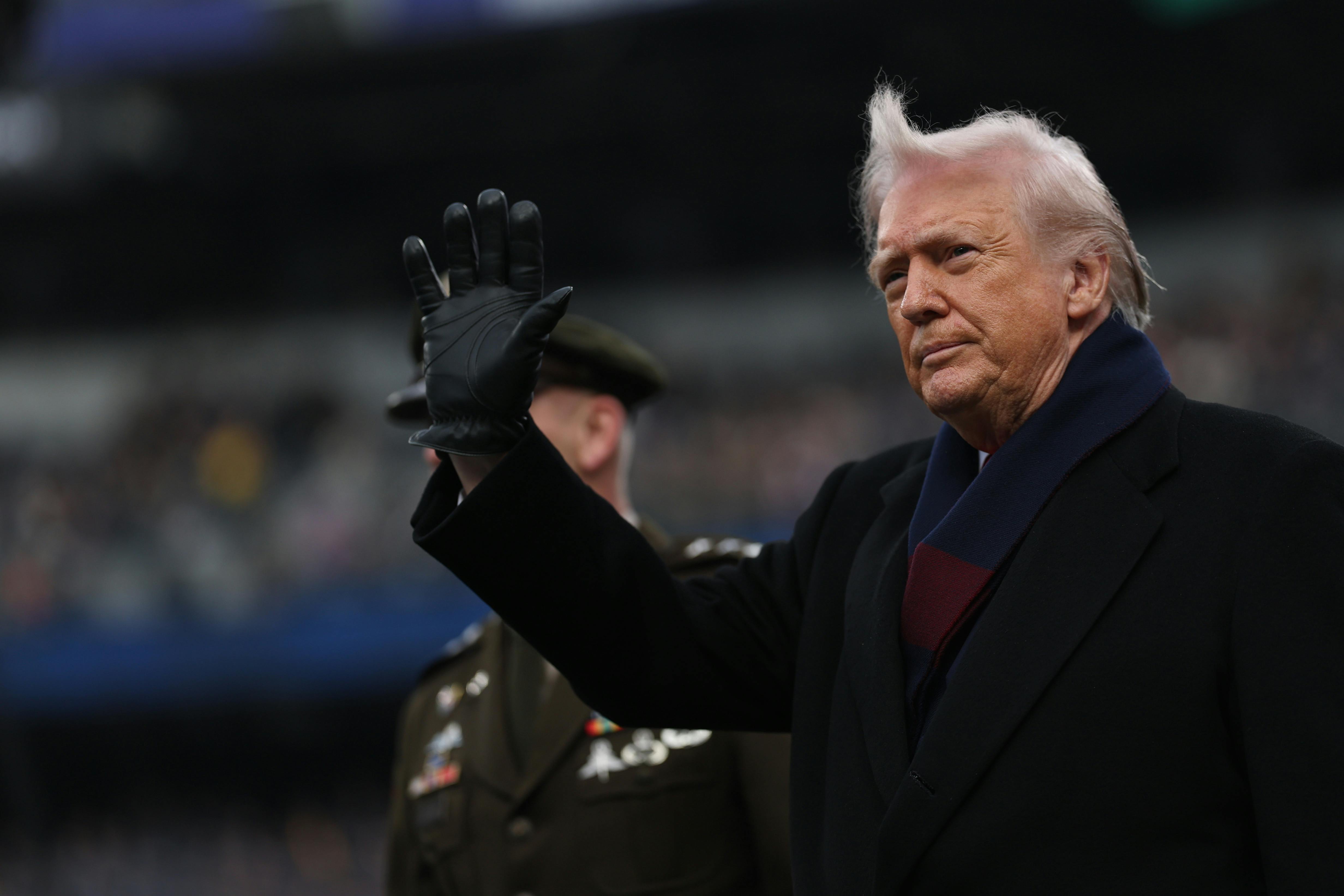 Donald Trump waves while standing on the field at the Army-Navy football game