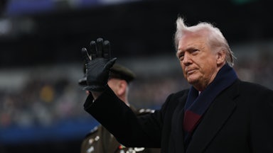 Donald Trump waves while standing on the field at the Army-Navy football game