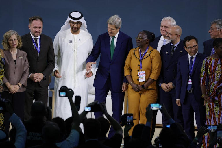 Sultan Ahmed Al Jaber and John Kerry stand among others in front of a crowd taking pictures.