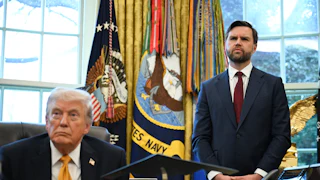 Donald Trump sits at his desk in the Oval Office of the White House as JD Vance stands next to him