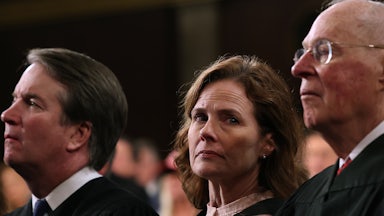 Amy Coney Barrett looks toward the camera, with Kavanaugh and Kennedy on either side of her.