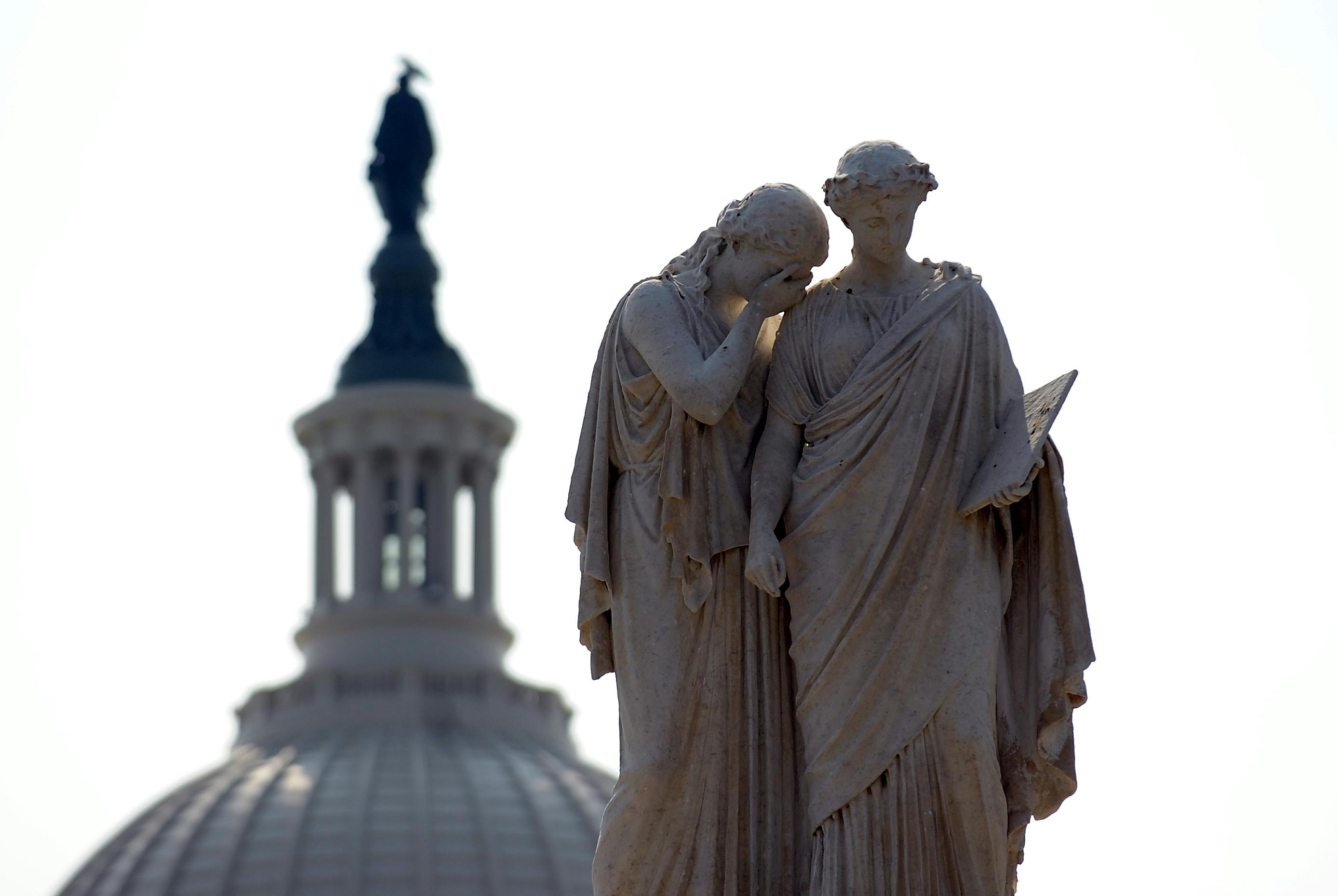 Statues depicting Grief and History stand watch over the U.S. Capitol.