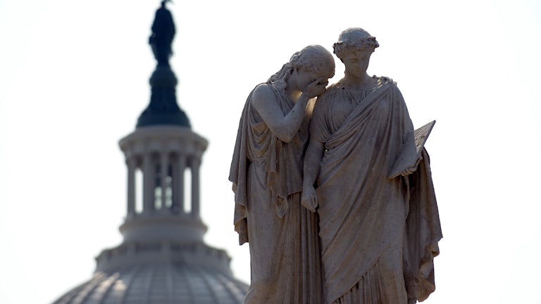Statues depicting Grief and History stand watch over the U.S. Capitol.