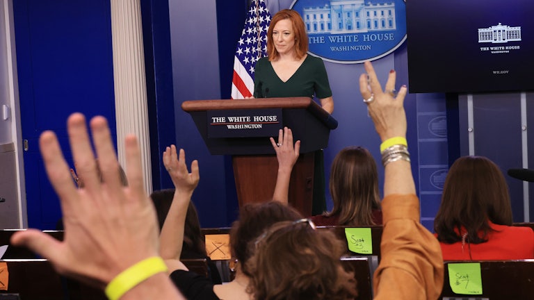 Members of the press raise their hands as Jen Psaki conducts a news conference.