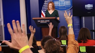 Members of the press raise their hands as Jen Psaki conducts a news conference.