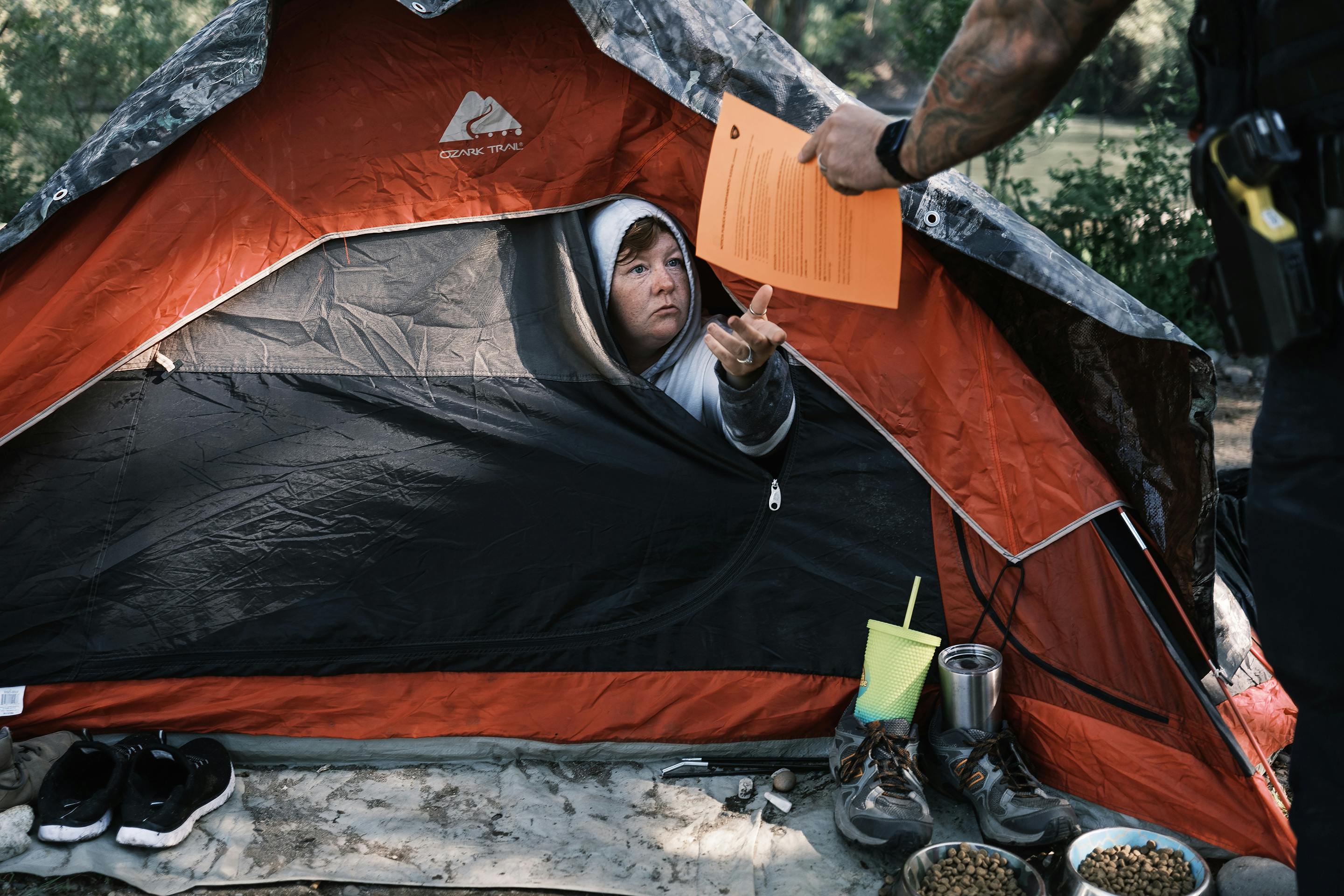 Officer Tim Artoff handed Terry Goodloe an order to vacate at Baker Park in Grants Pass, Oregon, in April 2024.