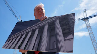 Donald Trump holds artists renderings as he talks to reporters about his proposed White House ballroom.