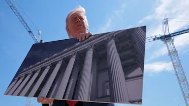 Donald Trump holds artists renderings as he talks to reporters about his proposed White House ballroom.