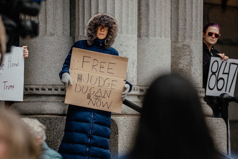 A person holds up a sign that says "Free Judge Dugan now" during a protest outside the U.S. Courthouse in Milwaukee in support of Judge Hannah Dugan