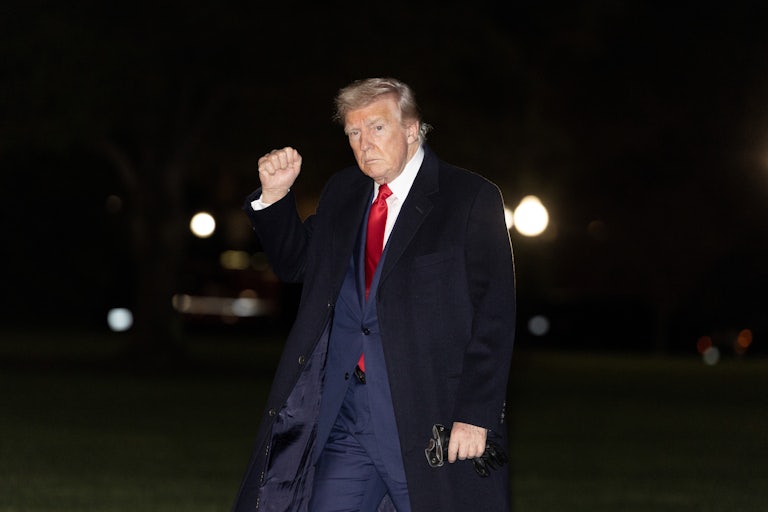 Donald Trump raises his fist while walking outside the White House