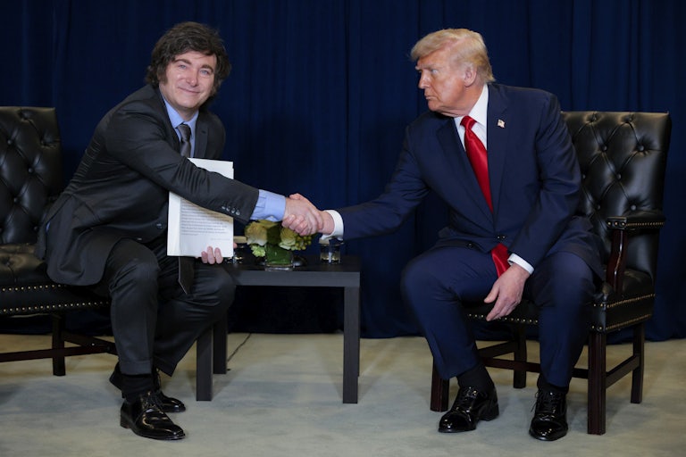 Argentinian President Javier Milei and U.S. President Donald Trump shake hands while sitting next to each other