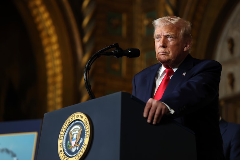 Donald Trump stands at a podium on stage.