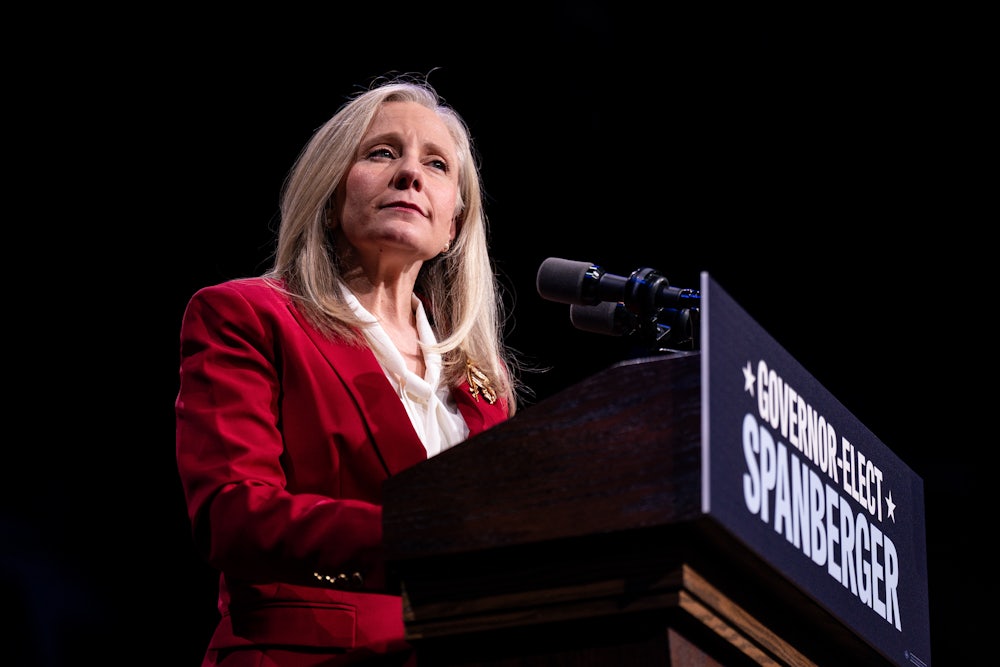 Abigail Spanberger stands at a podium while wearing a red blazer.