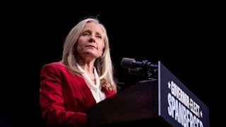 Abigail Spanberger stands at a podium while wearing a red blazer.