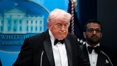 Donald Trump presses his lips together while standing at the podium in the White House press briefing room