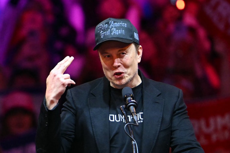 Elon wears a black MAGA Hat