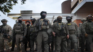 Federal agents hold back protesters outside a downtown ICE facility in Portland, Oregon.