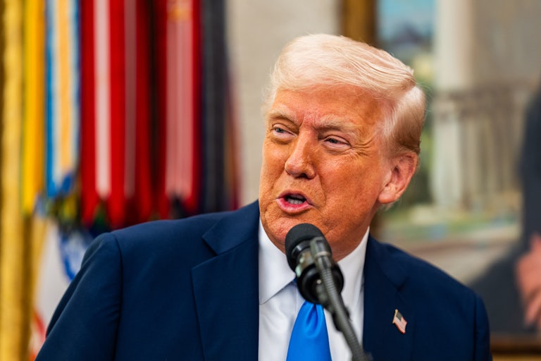 Donald Trump speaks into a microphone in the Oval Office