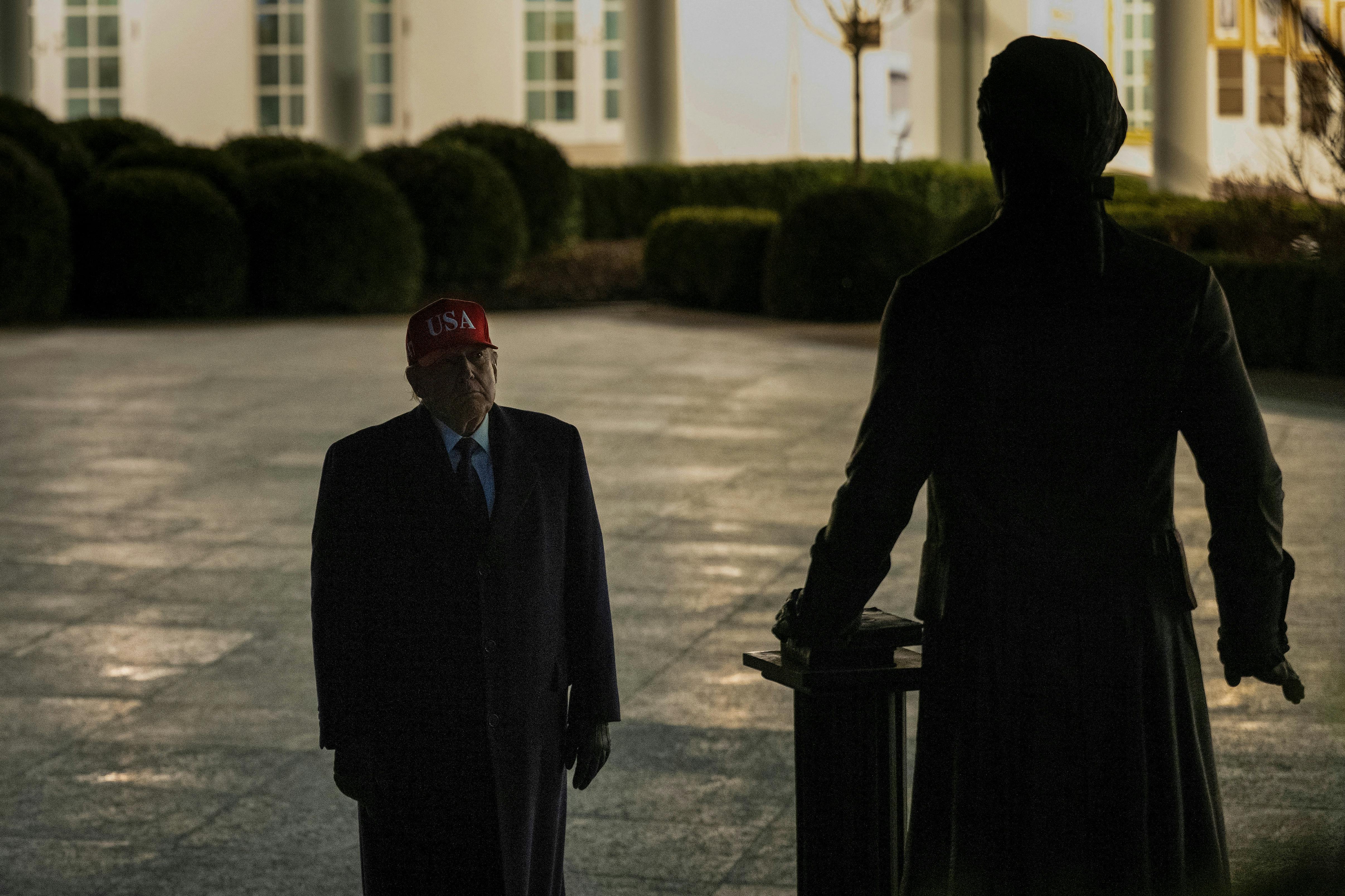 Donald Trump stands in the White House Rose Garden and looks at a statue of Thomas Jefferson