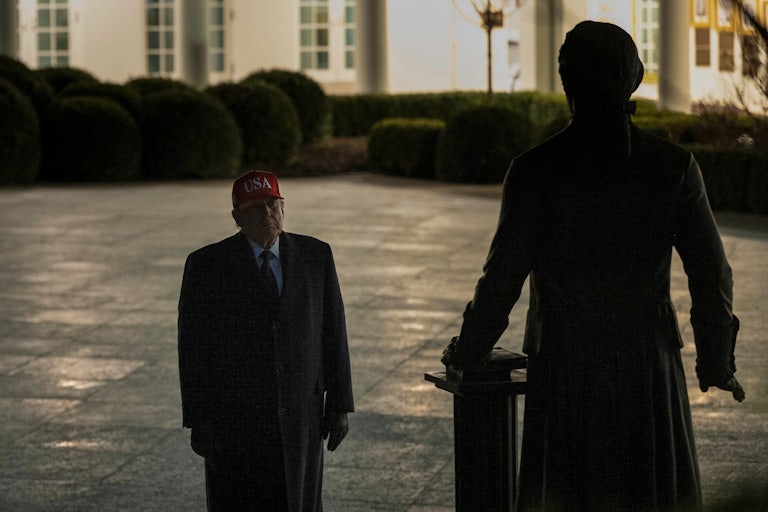 Donald Trump stands in the White House Rose Garden and looks at a statue of Thomas Jefferson