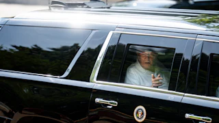 Donald Trump points out the car window as he rides in his motorcade