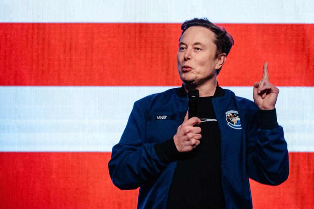 Elon Musk raises his finger while speaking on stage in Wisconsin