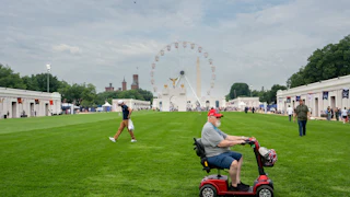 An old man on a riding scooter visits the Great American State Fair, which is very sparsely attended.