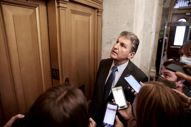 Joe Manchin waits for an elevator surrounded by reporters.