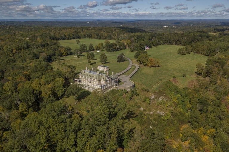 aerial view of a very large and very pretty house surrounded by a massive amount of land and trees.