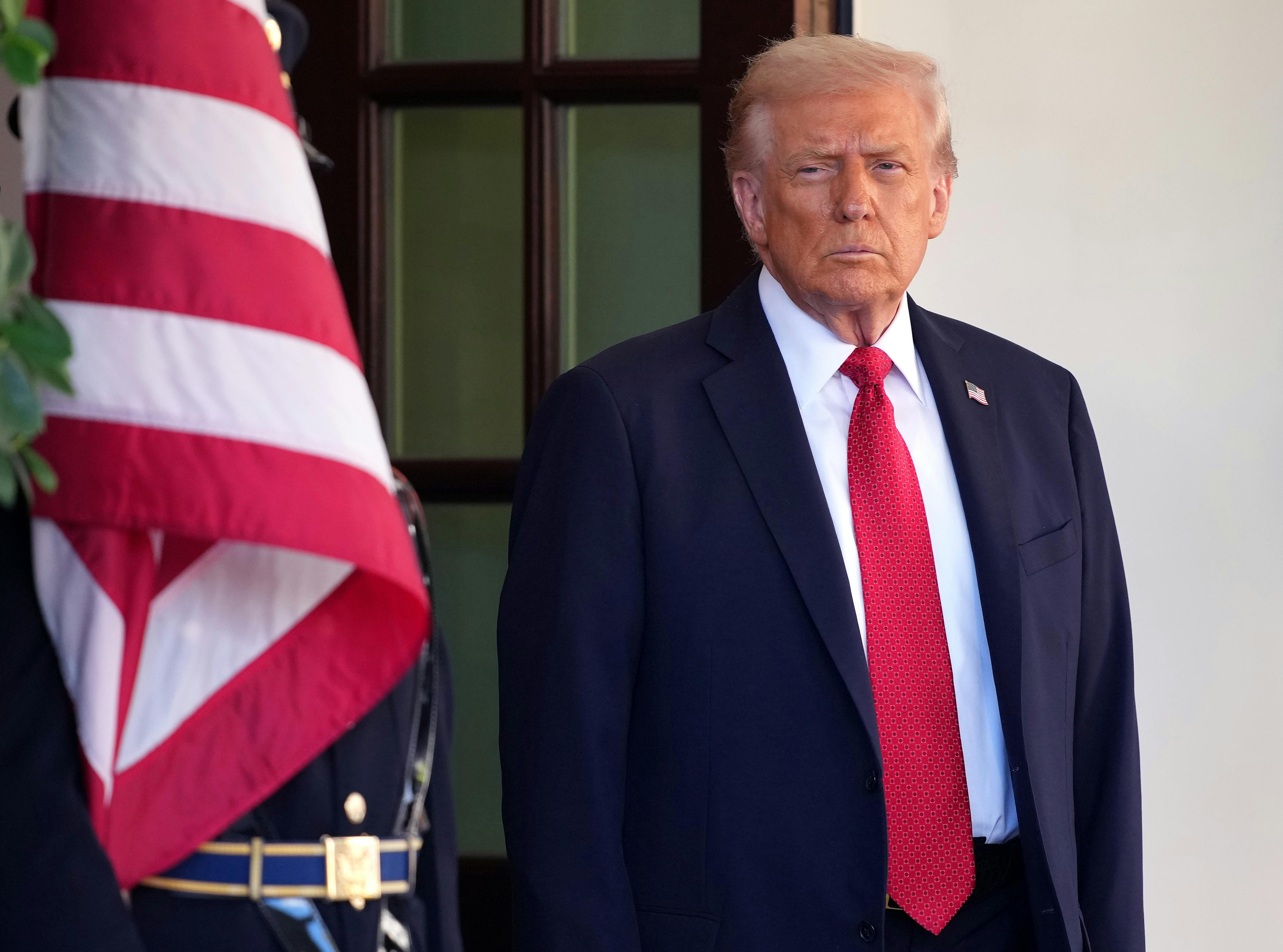 Donald Trump stands near a U.S. flag.