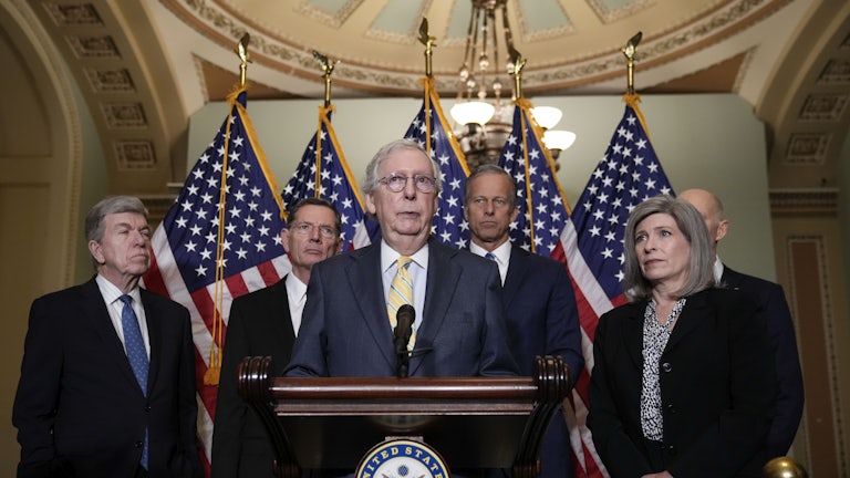 Senator Mitch McConnell stands with Senate Republican leadership behind a lectern, addressing reporters.