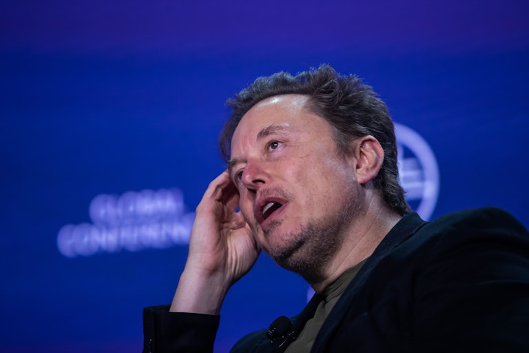 Elon Musk scratches his head at an event