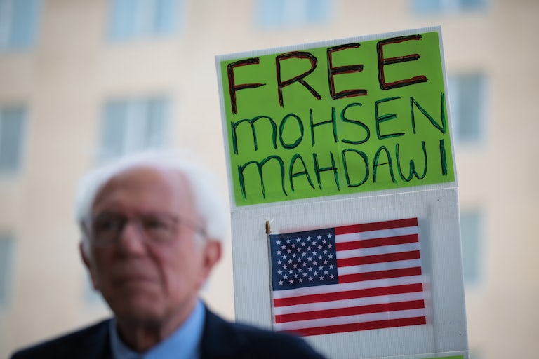 Senator Bernie Sanders stands in front of a sign that says, "Free Mohsen Mahdawi"