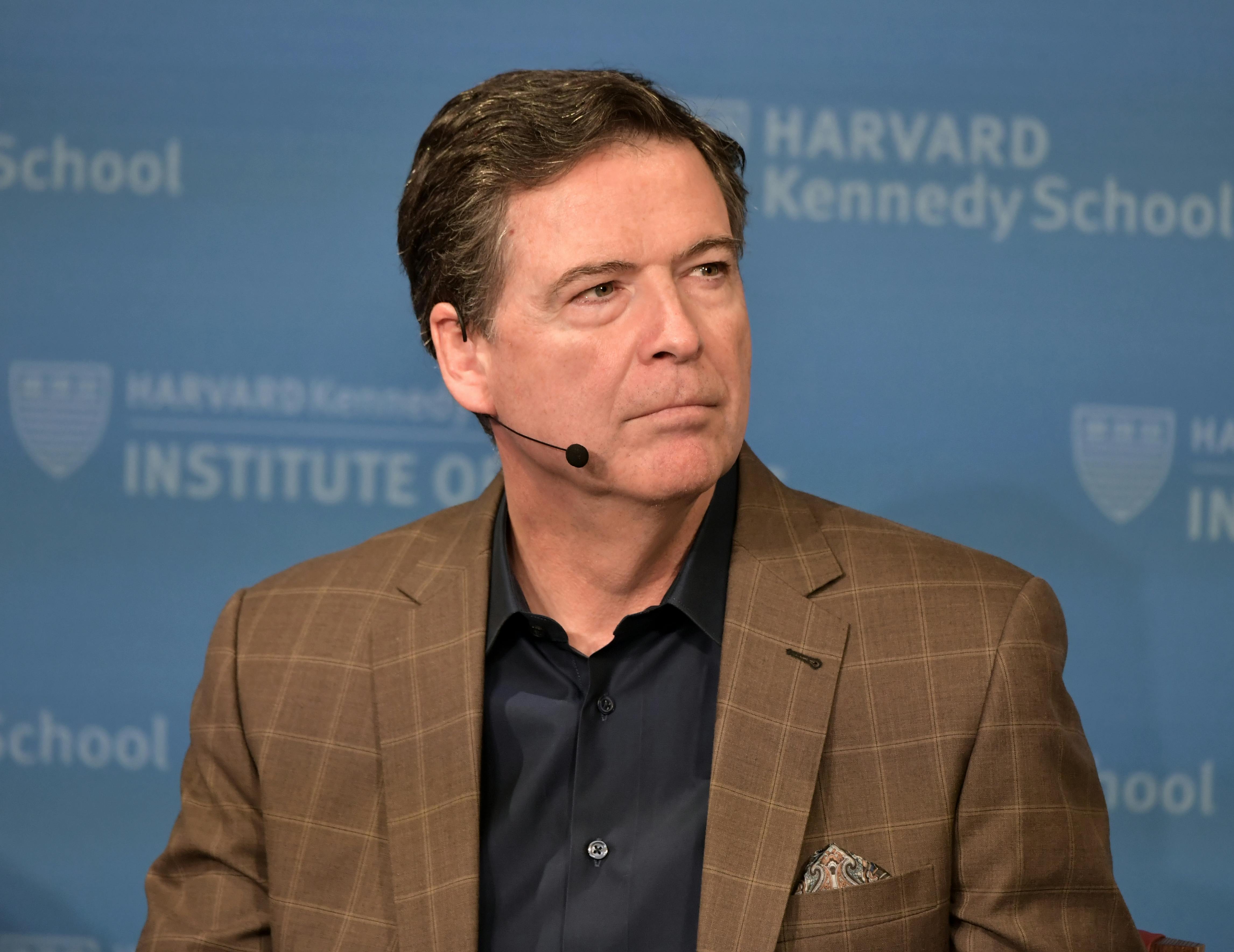 Former FBI Director James Comey wears a headset microphone while sitting on stage