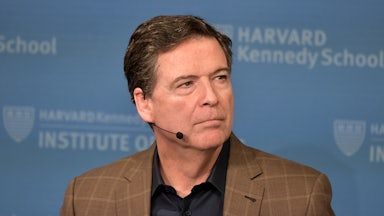 Former FBI Director James Comey wears a headset microphone while sitting on stage