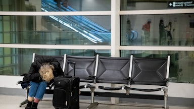 A woman seated in airport folds in on herself.