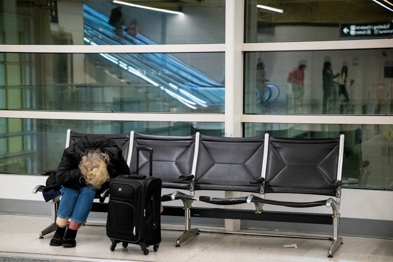 A woman seated in airport folds in on herself.