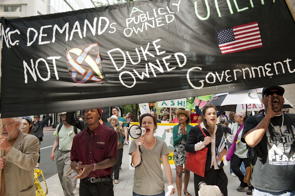 Protesters shout into a megaphone and carry signs.