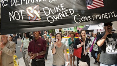 Protesters shout into a megaphone and carry signs.